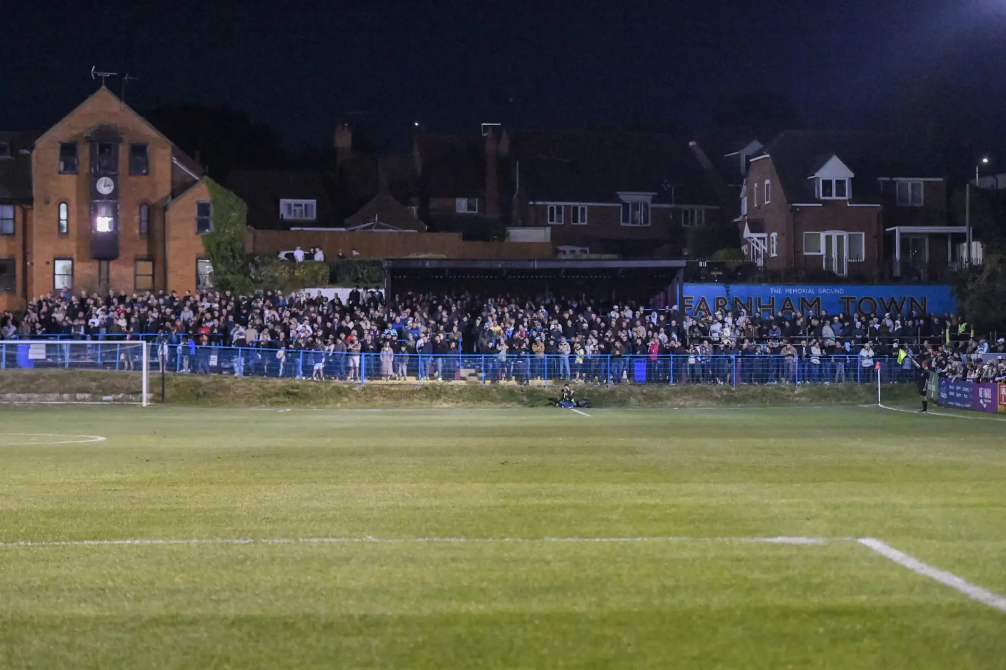 A packed floodlit terrace at Farnham Town's Memorial Ground on a match night