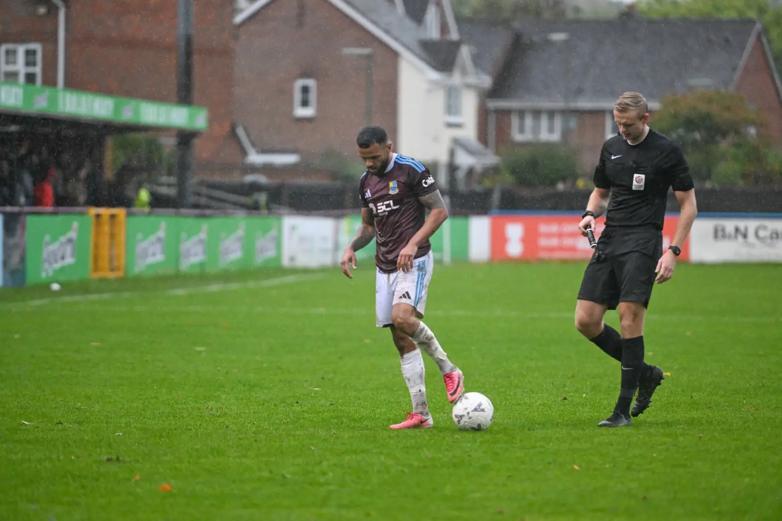 A player and referee on a rain-soaked non-league pitch