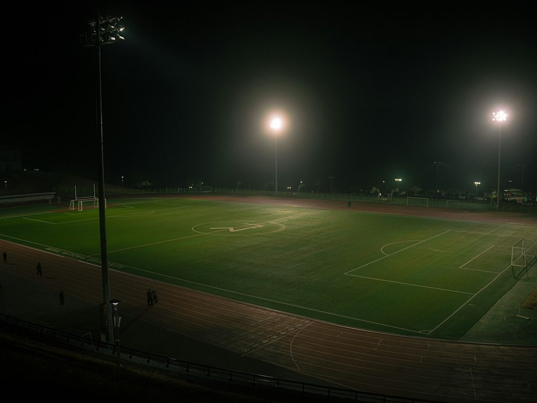 A small floodlit ground with a single stand