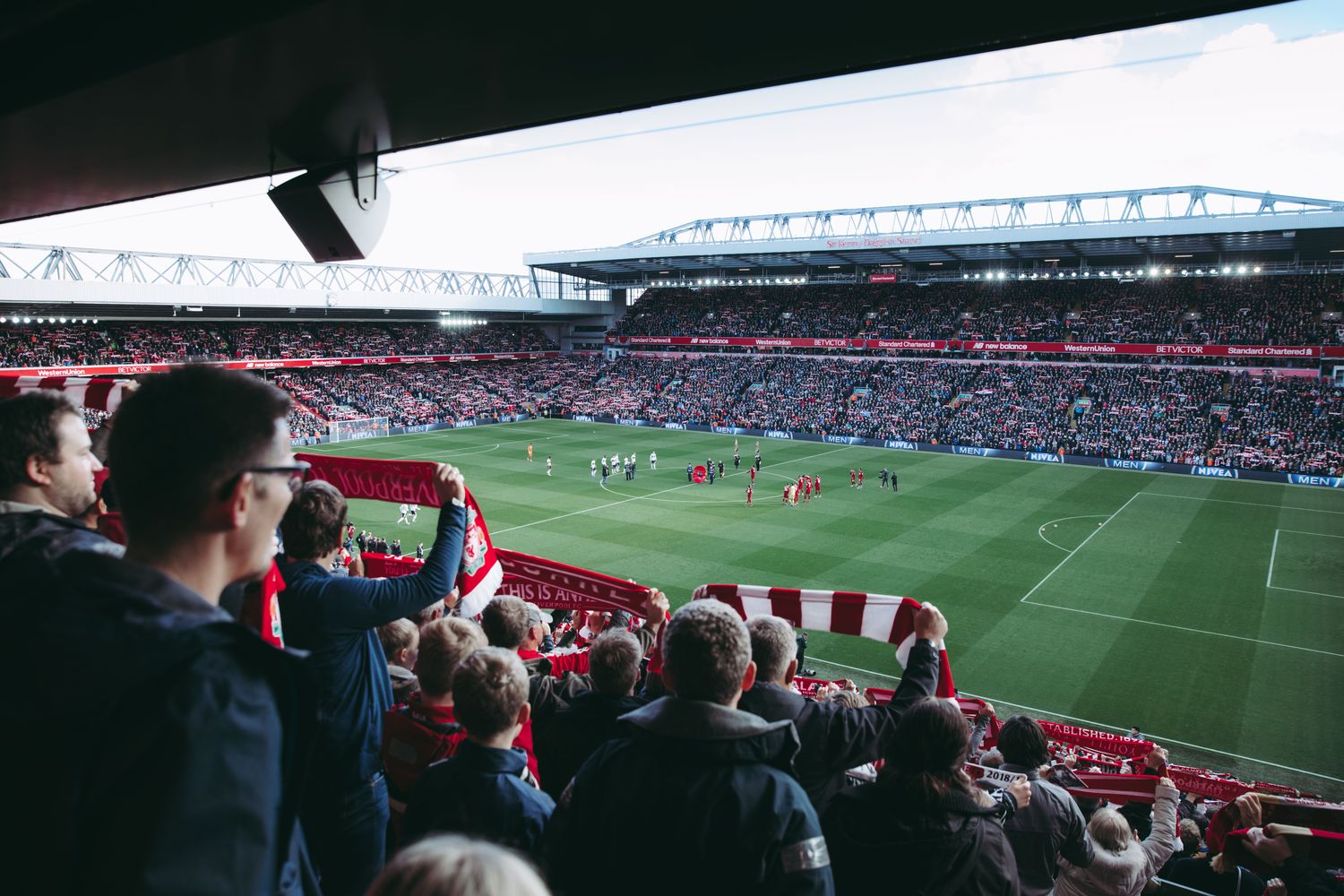 Supporters holding scarves aloft in a full stand at Anfield