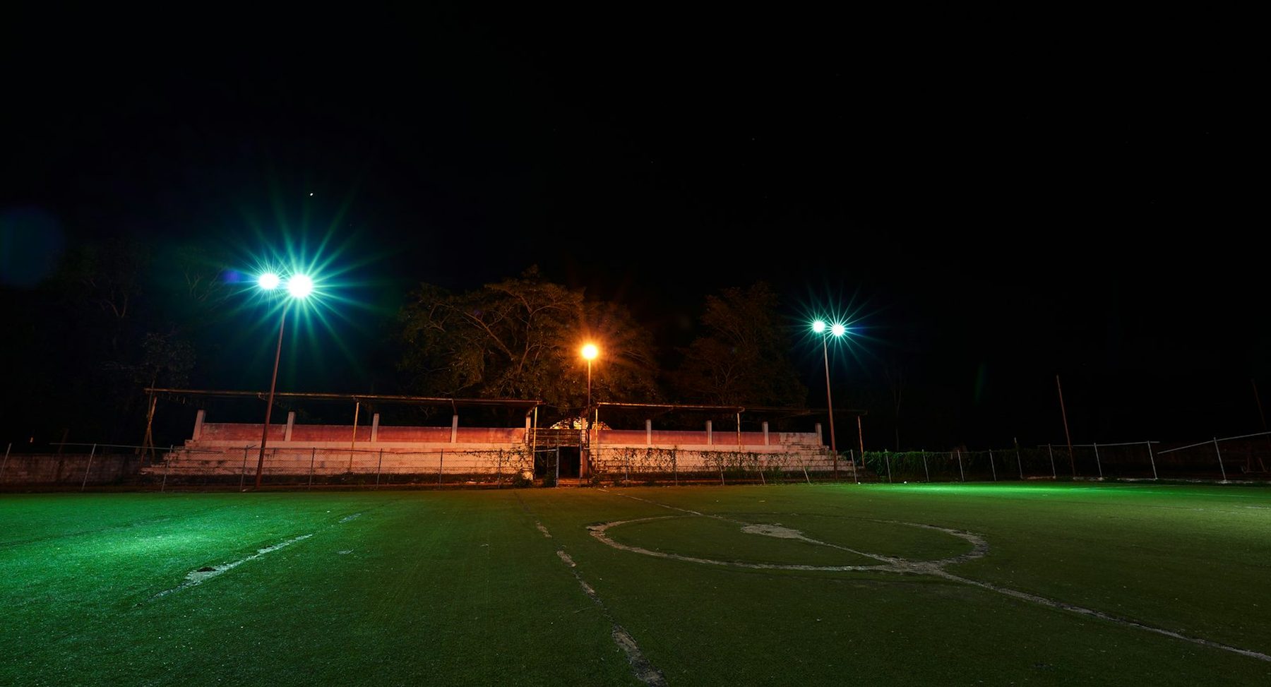 A small floodlit ground with a single stand at night