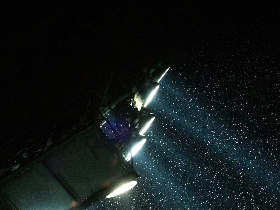 Floodlights burning through rain over a ground at night